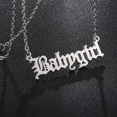 Silver 'Babygirl' necklace on a black textured background