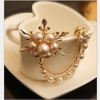 Pearl and gold brooch on a white cup