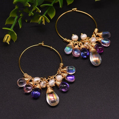 Gold hoop earrings with colorful beads on a dark background