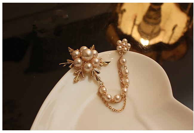 Pearl brooch on a white stand dish with a dark background