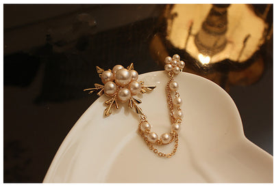 Pearl brooch on a white stand dish with a dark background