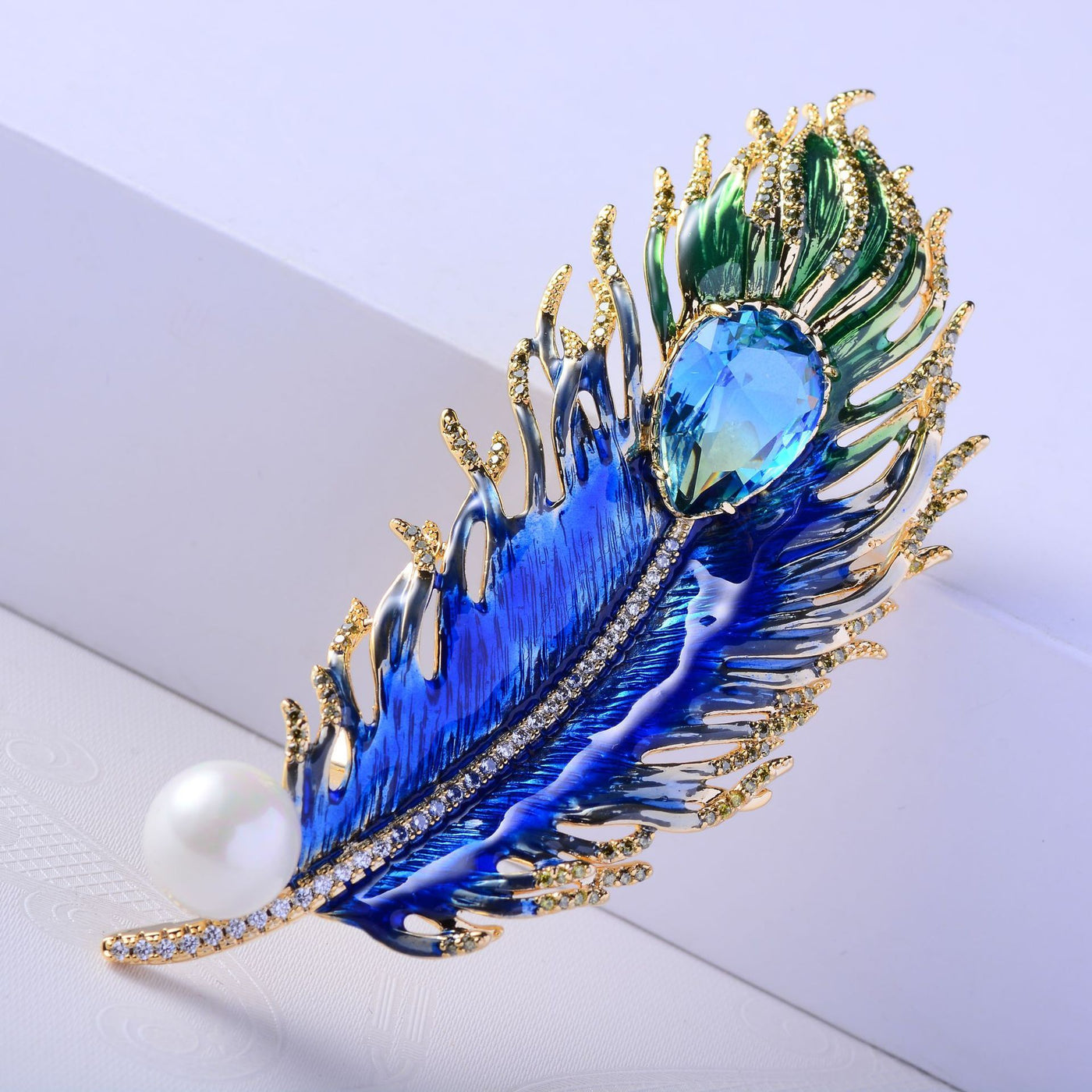Decorative feather brooch with blue gemstone and pearl on a light background