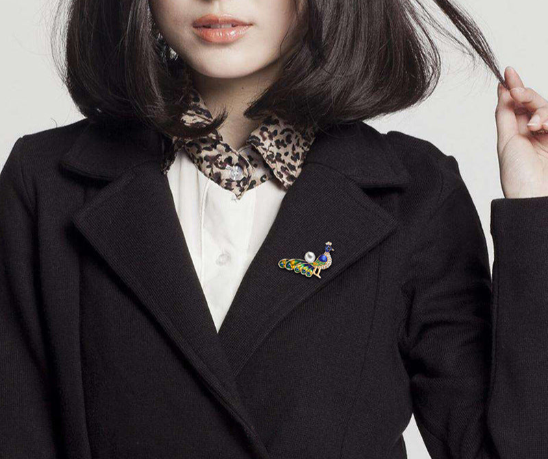 Person wearing a black coat with a leopard print collar and a decorative brooch.