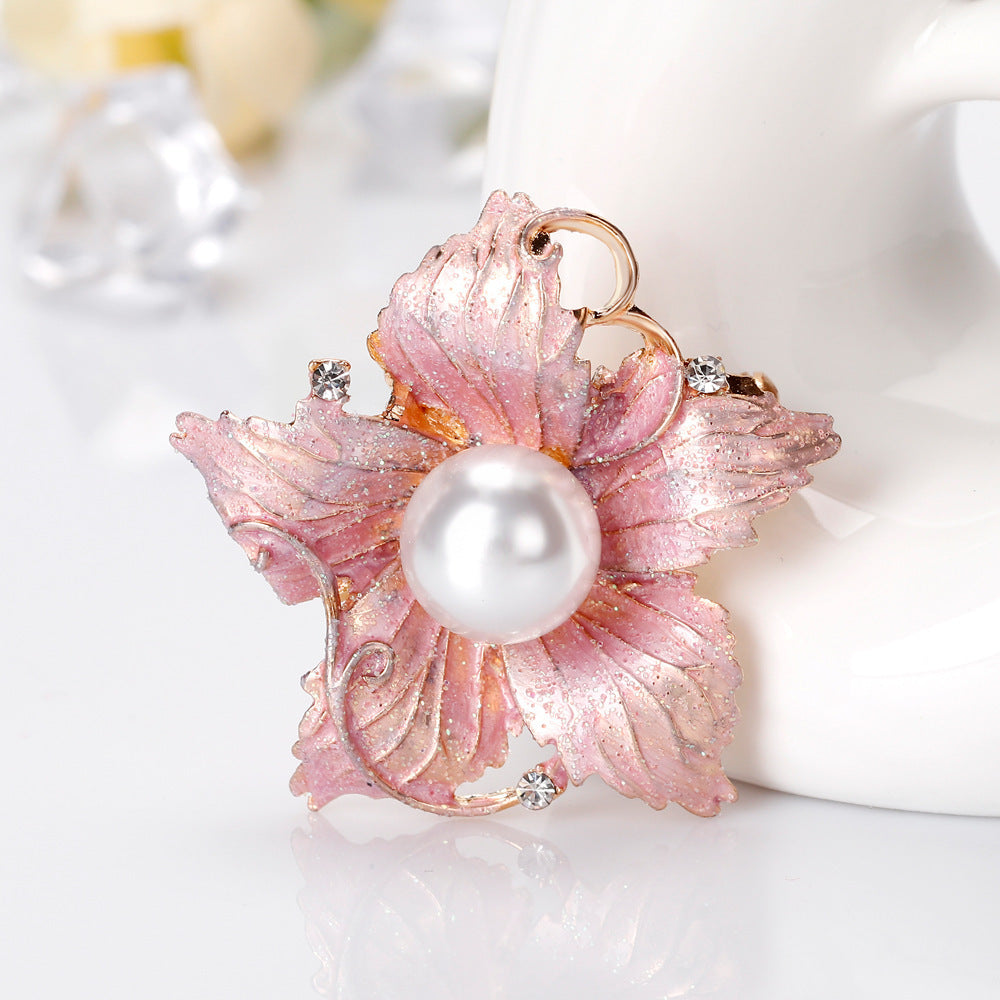 Pink floral brooch with a pearl center on a white background