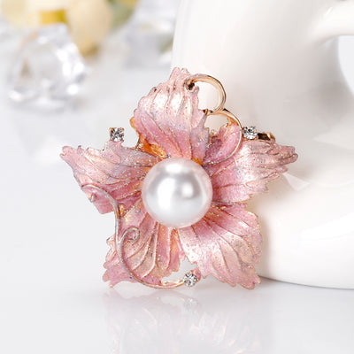 Pink floral brooch with a pearl center on a white background