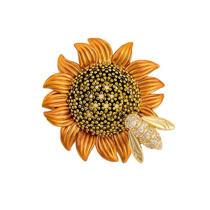 Gold sunflower brooch with a bee on a white background