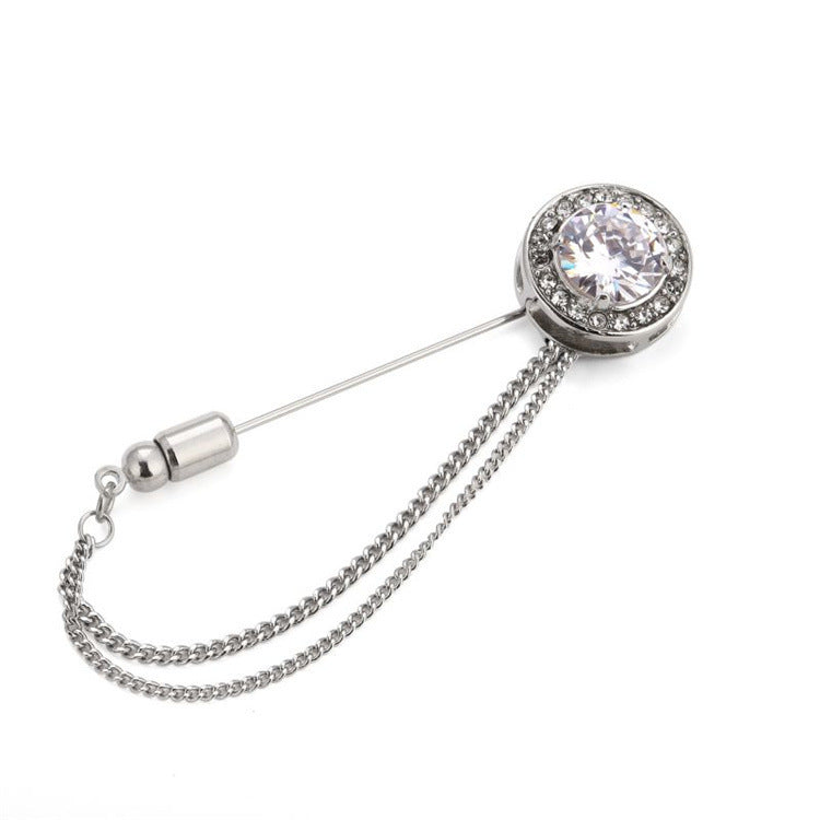 Silver brooch with a chain and clear gemstone on a white background