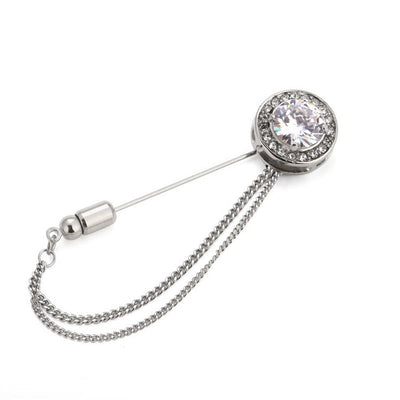 Silver brooch with a chain and clear gemstone on a white background