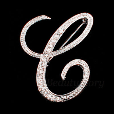 Silver brooch with letter 'C' design on a black background