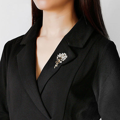 Woman wearing a black blazer with a decorative brooch on a plain background