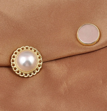 Close-up of a pearl magnetic brooch and its magnet on a brown fabric background