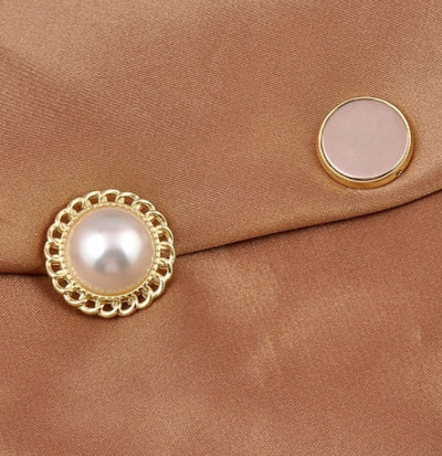 Close-up of a pearl magnetic brooch and its magnet on a brown fabric background