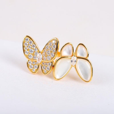 Gold butterfly-shaped brooch with gemstones on a light background