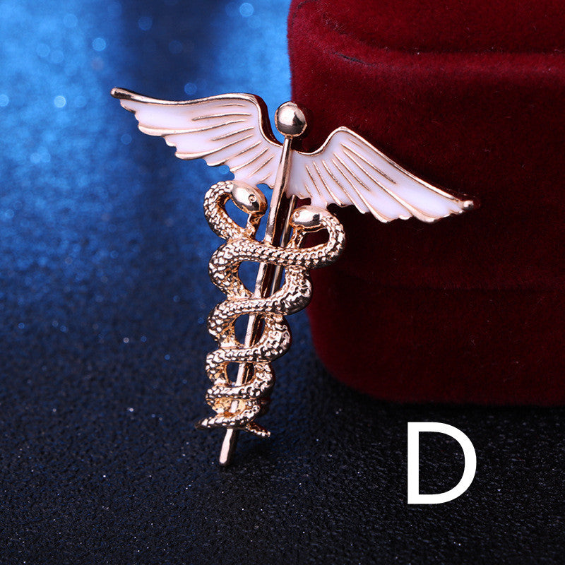 Gold medical caduceus symbol brooch on a dark background