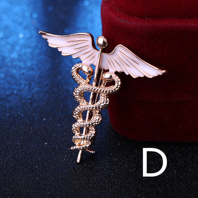 Gold medical caduceus symbol brooch on a dark background