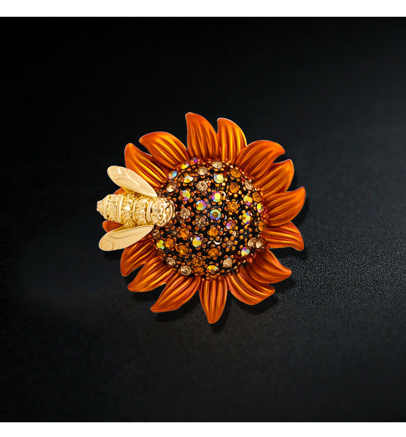 Sunflower-shaped brooch with gemstones and a bee on a black background