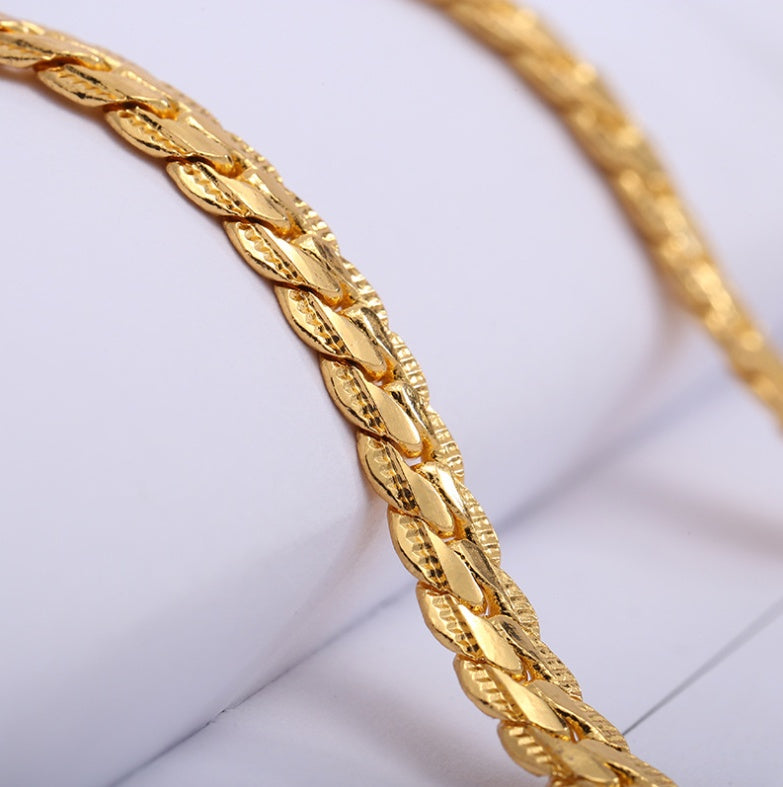 Gold braided bracelet on a light gray background