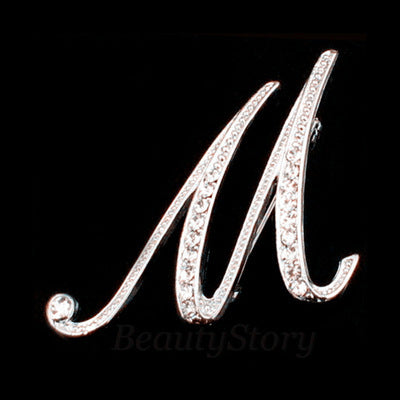 Silver brooch with the letter 'M' on a black background