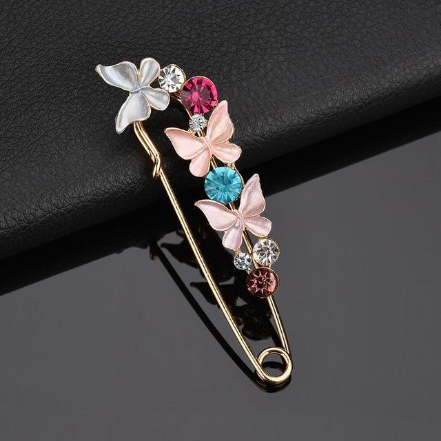 Decorative brooch with butterflies and gemstones on a dark background