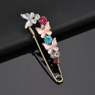 Decorative brooch with butterflies and gemstones on a dark background