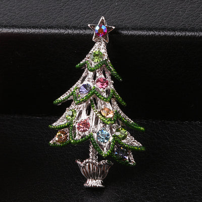 Decorative Christmas tree brooch with colorful gemstones on a black background