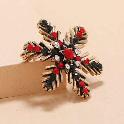 Decorative brooch with red, green, and clear gemstones on a beige background