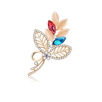 Decorative brooch with colorful gemstones and gold detailing on a white background