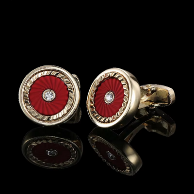 Gold cufflinks with red circular design and diamond center on a black background