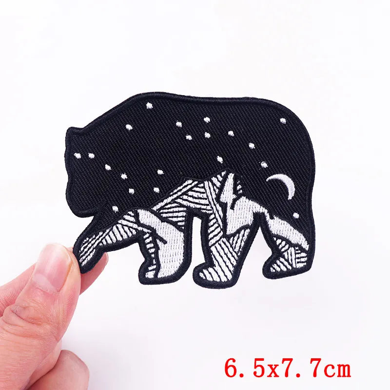 Black and white bear patch held by a hand with size measurement on a white background