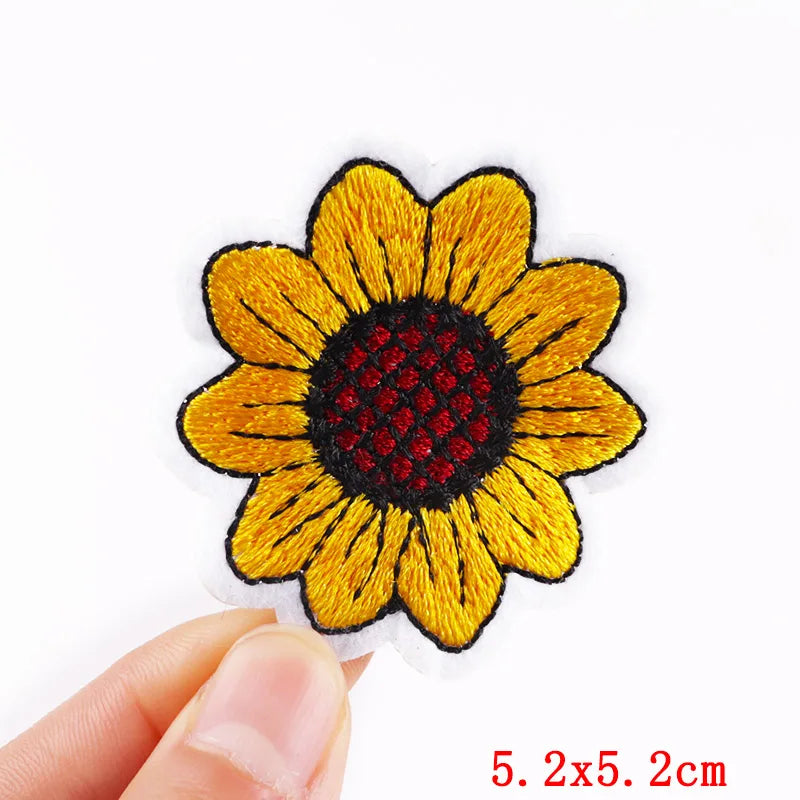 Sunflower-shaped patch held by a hand with dimensions indicated.