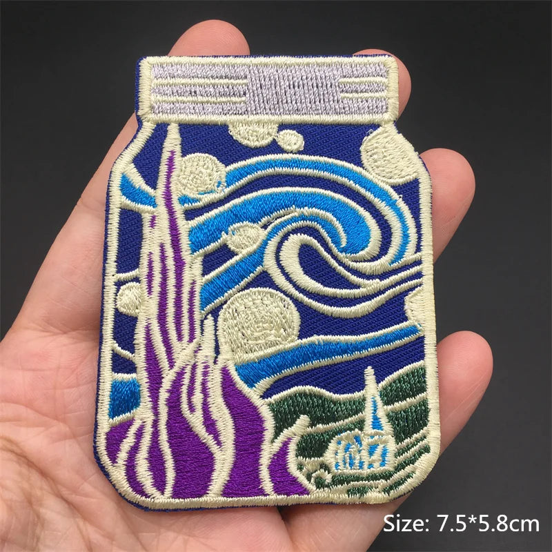 Embroidered patch of a bottle with wave design held in a hand, on a dark background.