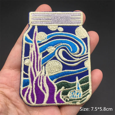 Embroidered patch of a bottle with wave design held in a hand, on a dark background