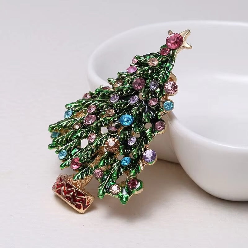 Decorative Christmas tree brooch with colorful gemstones on a white dish and on a white background