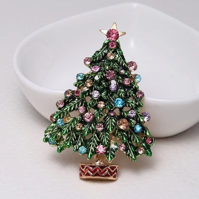 front view of Decorative Christmas tree brooch with colorful gemstones on a white dish and background