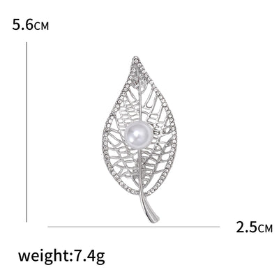 Silver leaf-shaped brooch with pearl center and measurements on a white background