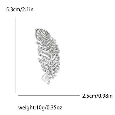 Silver feather-shaped brooch with pearl center and measurements on a white background