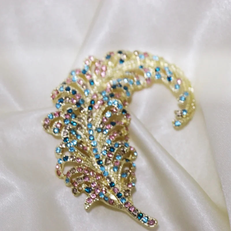 Decorative feather with colorful gemstones on a white fabric background