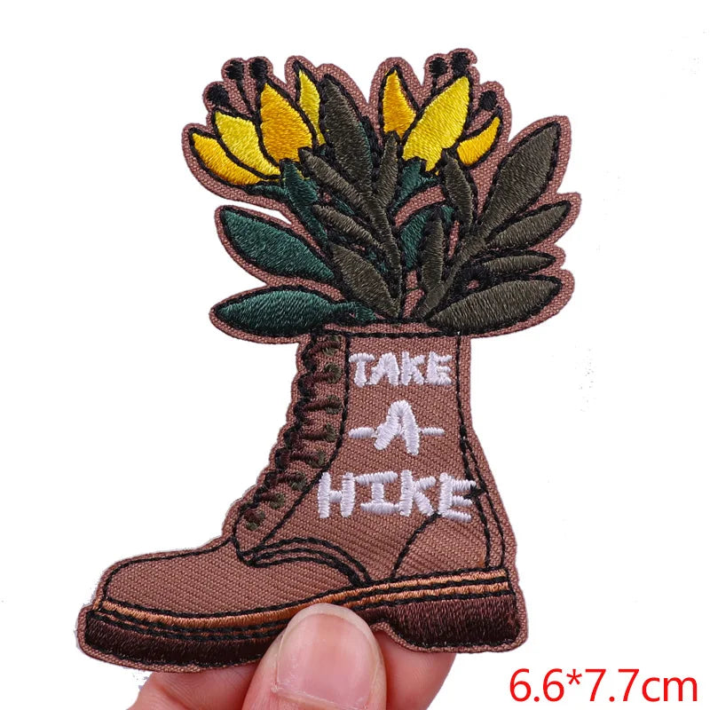Embroidered patch of a boot with flowers and 'Take a Hike' text on a white background