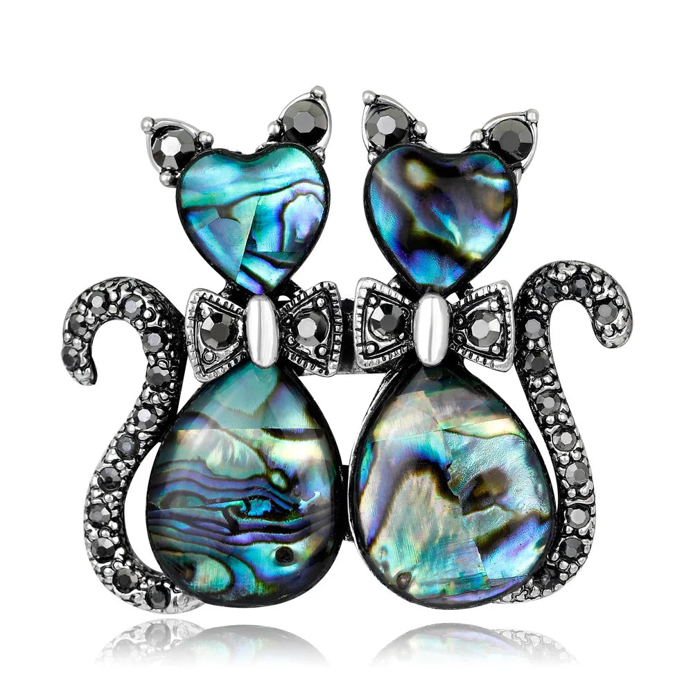 Cat-shaped brooch with abalone shell and crystal accents on a white background