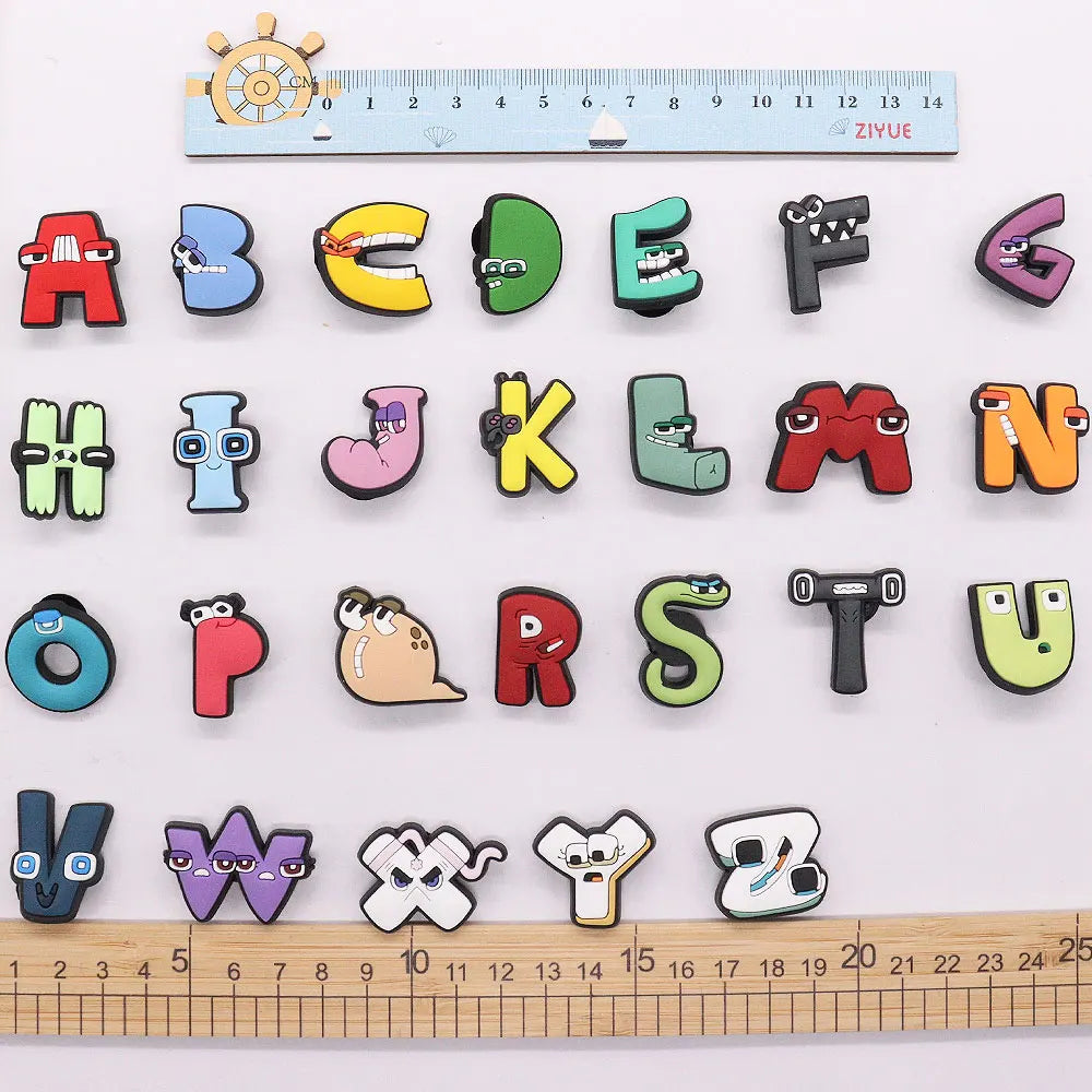 Colorful alphabet letter shoe charms with a ruler for scale on a white background