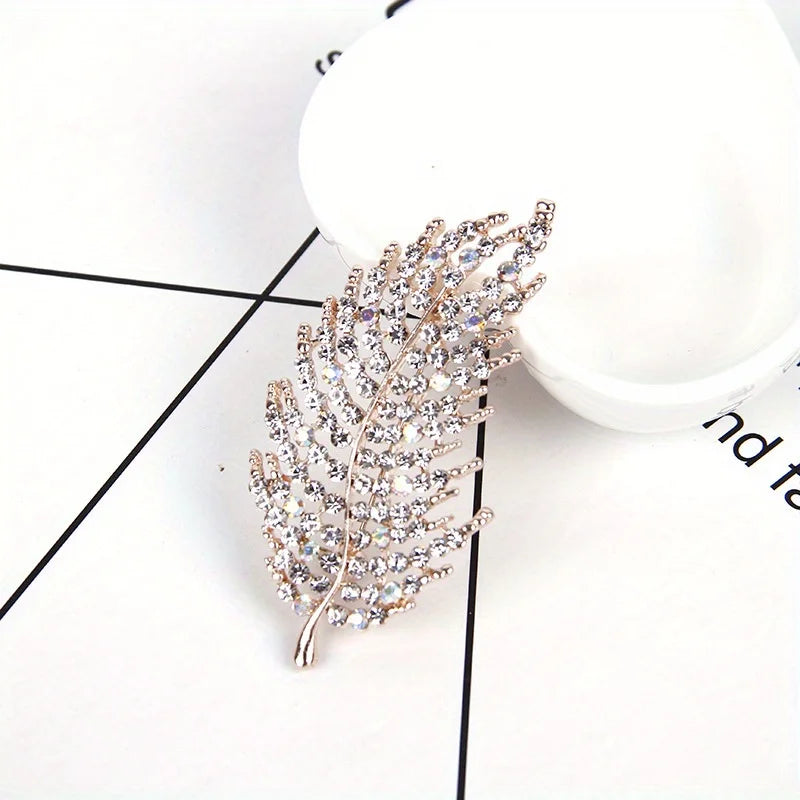 Decorative leaf-shaped brooch with crystals on a white background