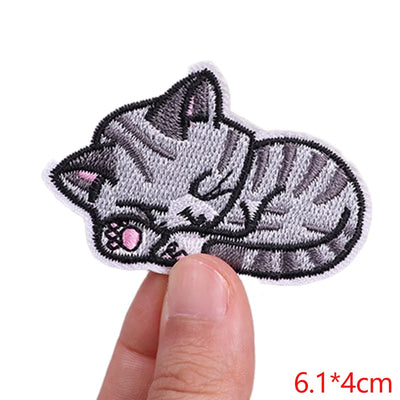 Cat-shaped patch held between fingers with size label '6.1*4cm' on a white background