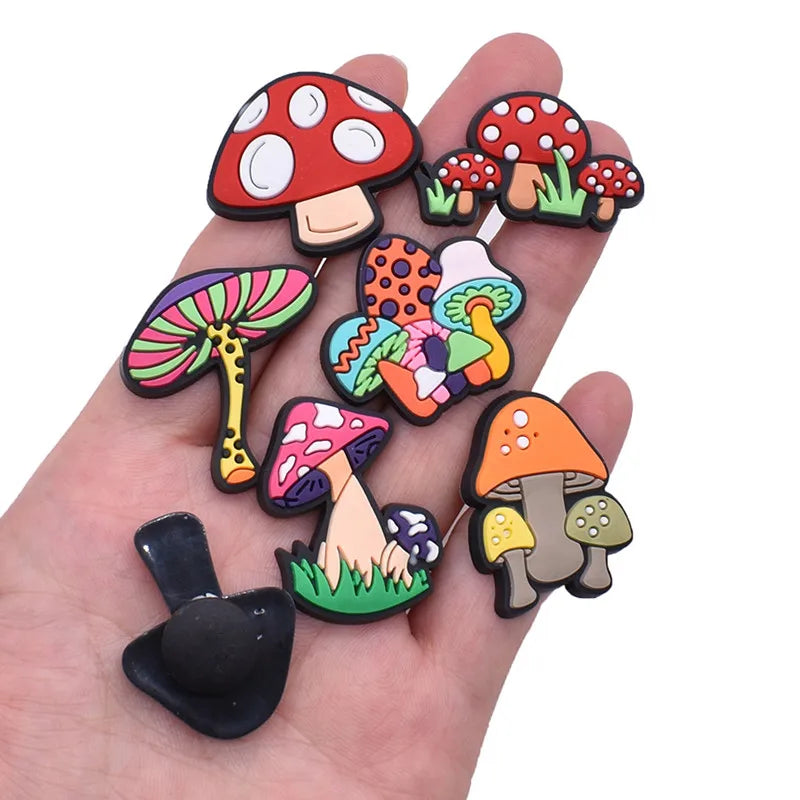 Colorful mushroom-shaped shoe pins held in a hand against a white background