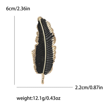 Black feather-shaped brooch with gold accents, shown with measurements on a white background.