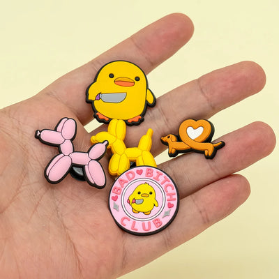 Hand holding four colorful shoe charms featuring cartoon characters on a light yellow background