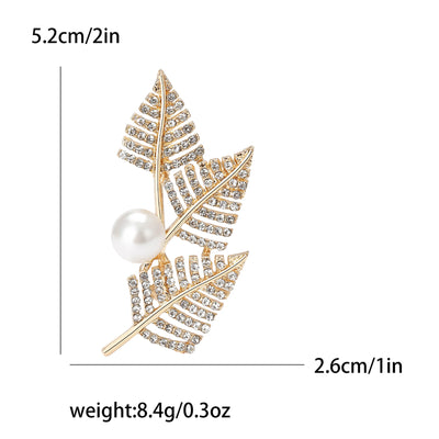 Gold leaf brooch with pearl center and measurements on a white background