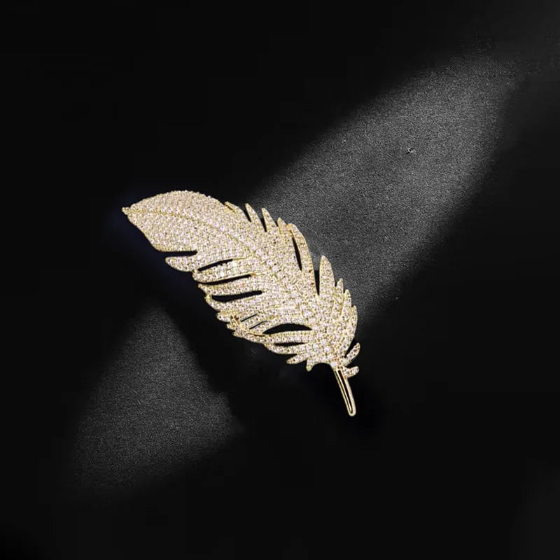 Gold feather-shaped brooch on a black background
