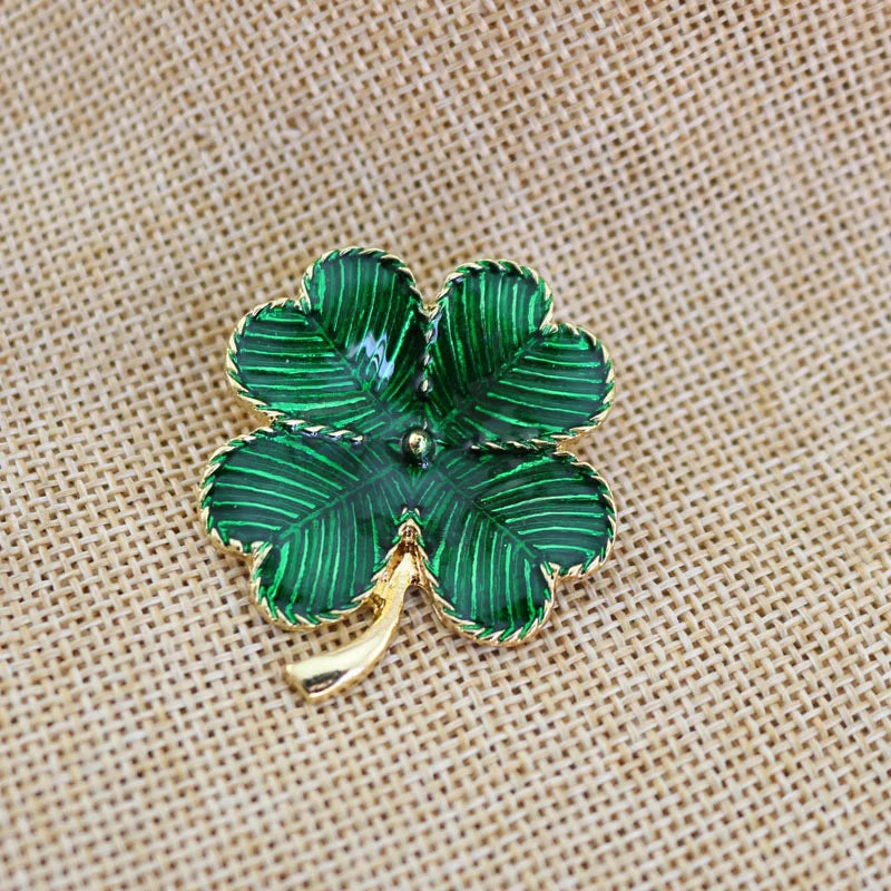 Green four-leaf clover brooch on a beige fabric background