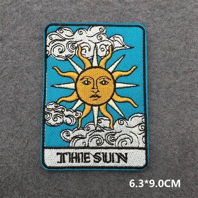 Embroidered patch of 'The Sun' tarot card design on a textured gray background