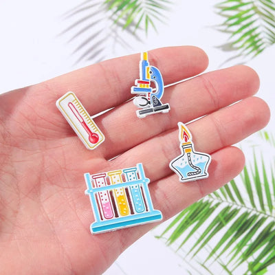 Set of colorful science-themed pins held in a hand with a light background